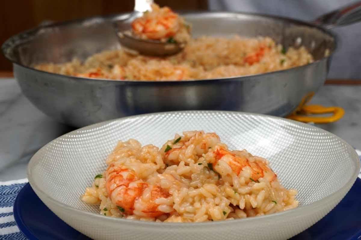Una padella e un piatto con risotto ai gamberi