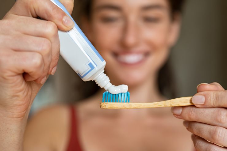 donna che mette il dentifricio sul suo spazzolino per i denti