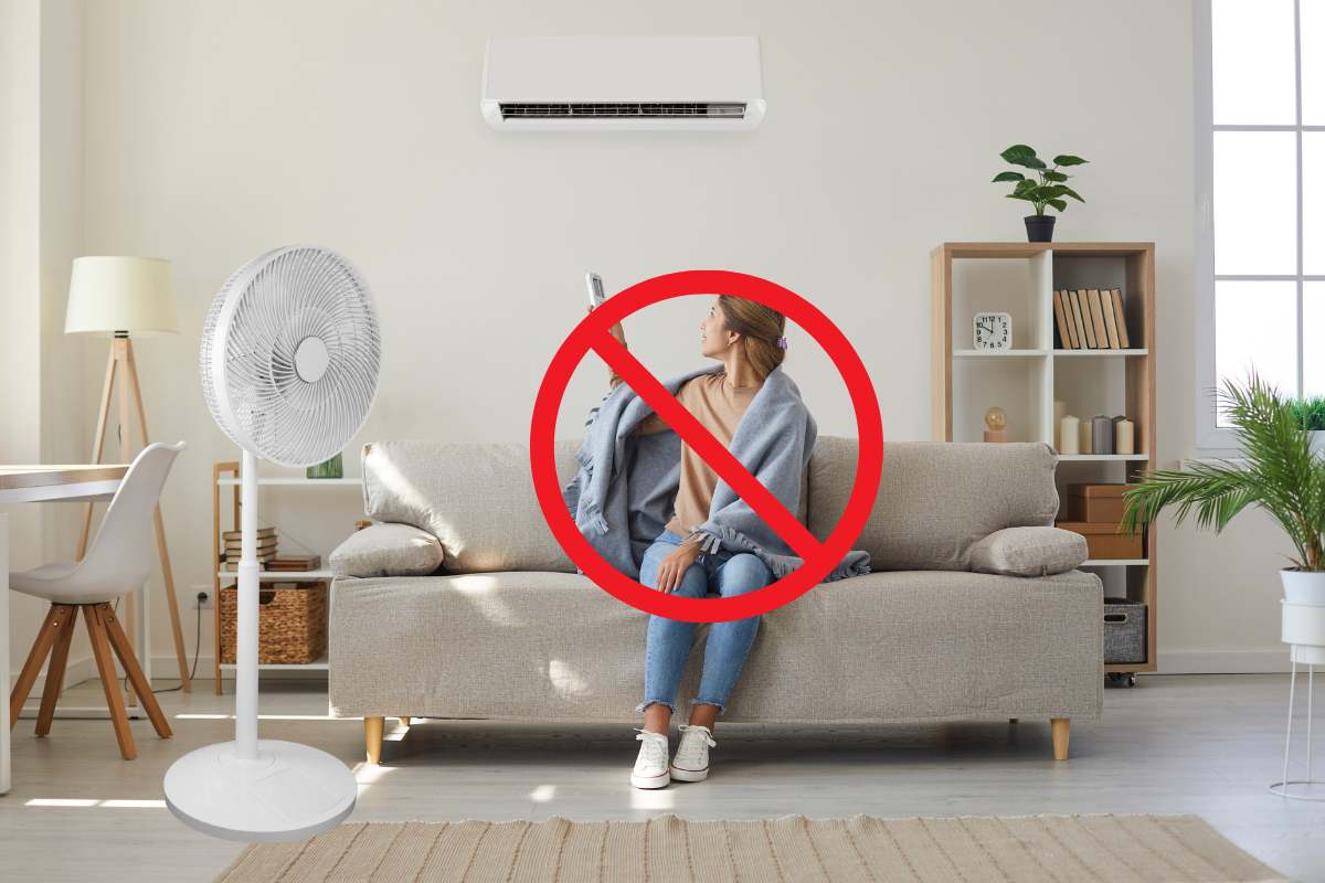 donna in un salone che usa un ventilatore e un condizionatore, con avanti un segnale di divieto