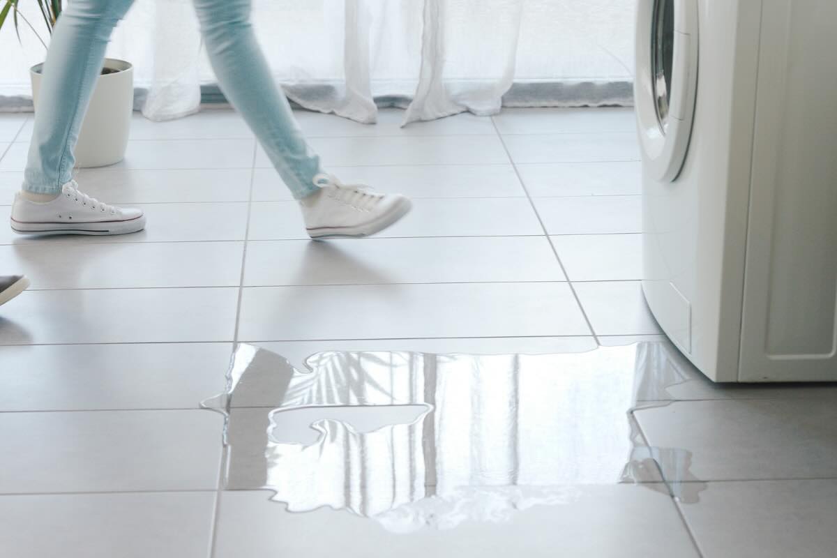gambe di ragazza vicino ad acqua accanto alla lavatrice