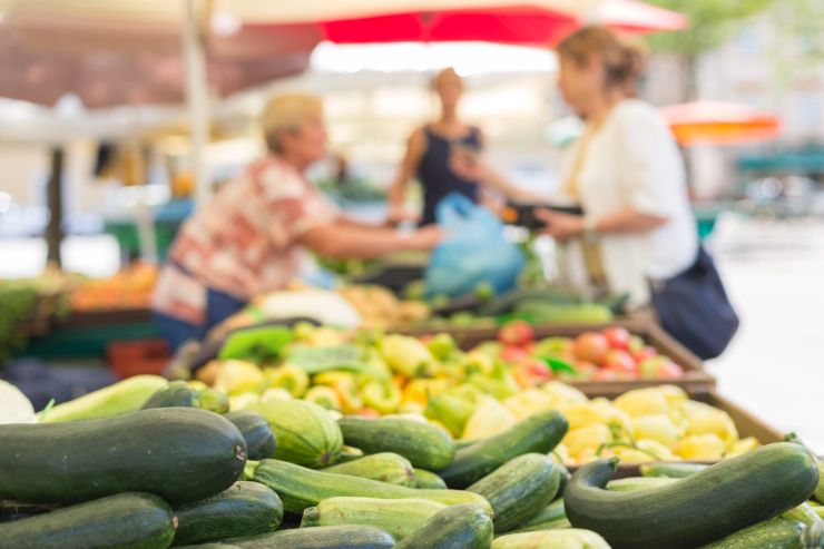 mercato con della frutta esposta, e una cliente che la sta comprando