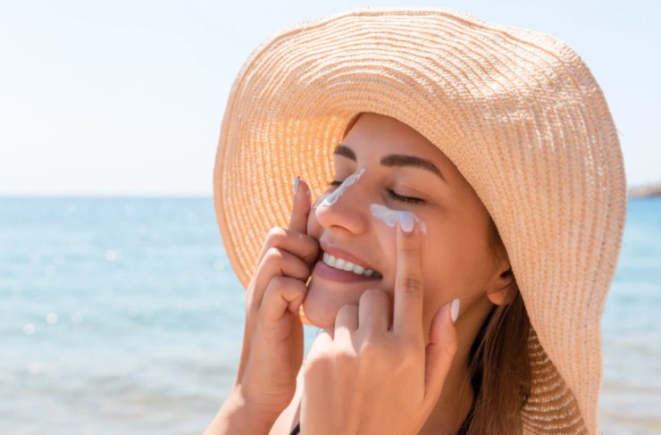 donna che si mette la crema solare in spiaggia