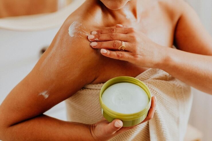 Donna applica crema su spalle e braccia 